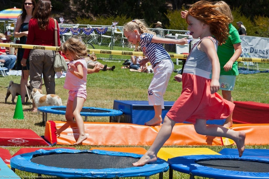 There are kids playing. It looks like a common park with lots of obstacle and rebounder. They are having their best time together. 