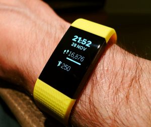 Garmin: A Garmin fitness timepiece on a wrist showing time, date, step count, and burned calories, with a yellow band.