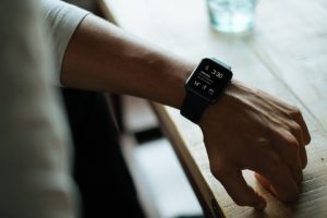 Garmin: Person wearing a Garmin timepiece while sitting at a table, with a water glass in the background.