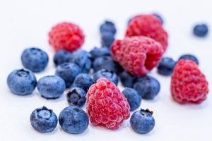 A close-up photograph capturing the vibrant colors and enticing textures of a homemade fruit drizzle cake adorned with fresh berries.