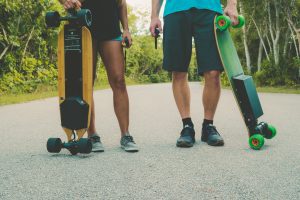 Two riders are holding their light electronic skateboard for travelling