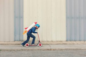 How To Select Racing Scooters: This child is practicing on fast riding with a toy rocket on his back as visualization of his speed. This is a great picture.