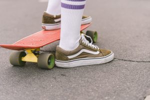 A man with a brown shoes placing his one foot on electric skateboard