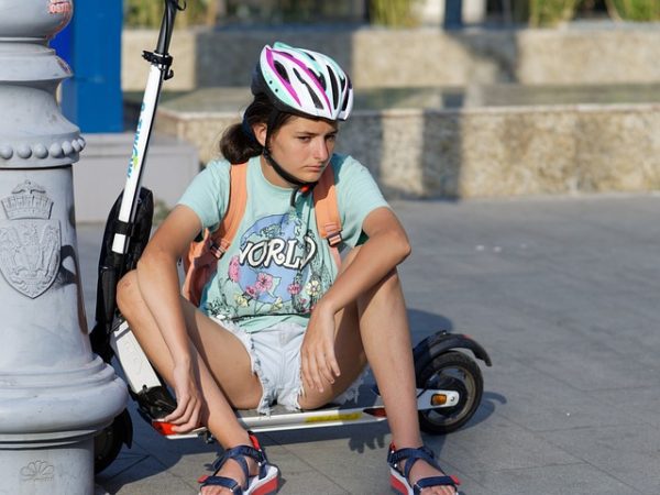 Teenager sitting on her scooter, wearing a helmet