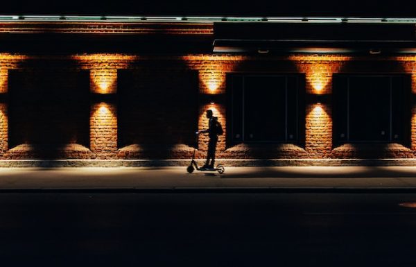 A man rides his scooter at night with its dim light.