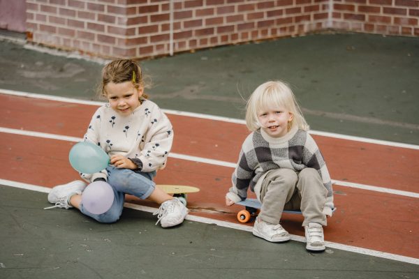 Preschoolers sitting on their skateboards.