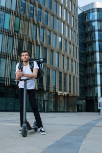 Man in front of a building on a scooter