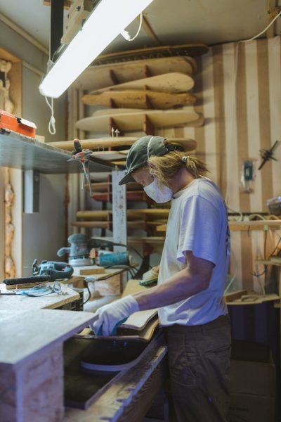 Skateboarding making: A man with mask and gloves makes a skateboard.