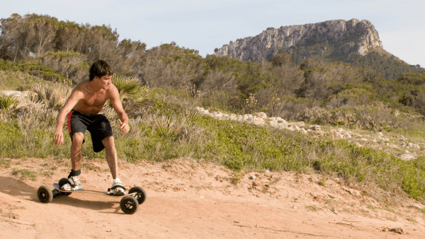 Shirtless guy balancing on his skateboard.