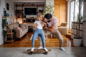 A skateboarder teaching his daughter skateboard riding