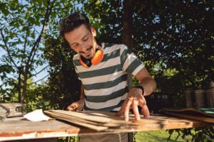 diy skateboards rack - Man is measuring wood to make personalized rack for skateboard.