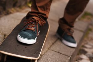 a black shoes with brown lace is on top of a skater's skateboard ready for a ride.