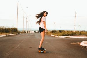 A young woman skateboarding on a street, showcasing speed and guidance.