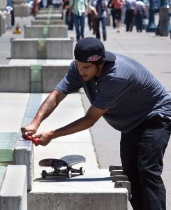 The man is using the skateboard wax to polish his board. This is a good way for a good looking board.