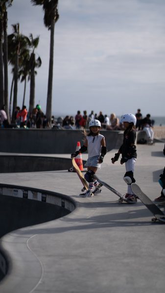 Two young riders with headgear practicing at a beachside park. 