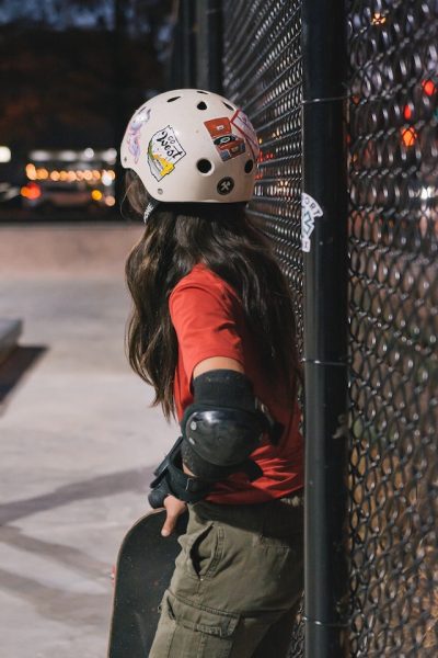 A skateboard rider wearing a headgear with stickers. 